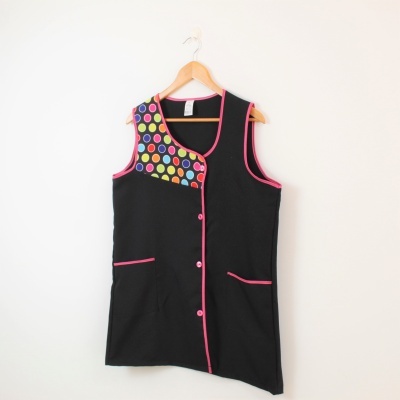 Colete preto com detalhe de círculos coloridos e acabamento rosa pendurado num cabide