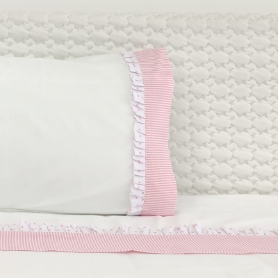Conjunto de cama com almofada branca e borda rosa às riscas com padrão de bolinhas cor-de-rosa e edredão branco texturizado