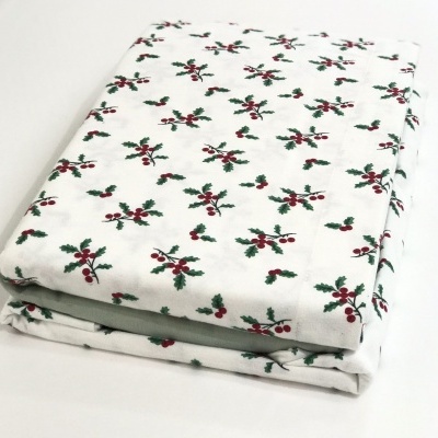 Toalha branca com padrão de folhas verdes e bagas vermelhas dobrada