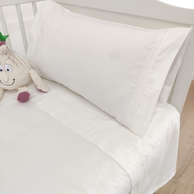 Jogo de cama branco com fronha bordada e brinquedo de pelúcia em cama infantil branca