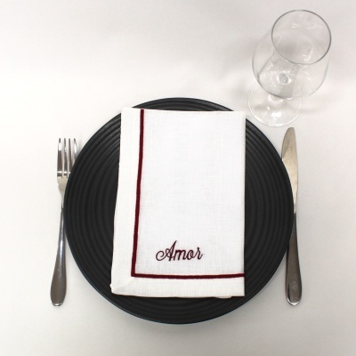 Conjunto de jantar com prato preto, guardanapo branco com bordado 'Amor', talheres e copo de vidro