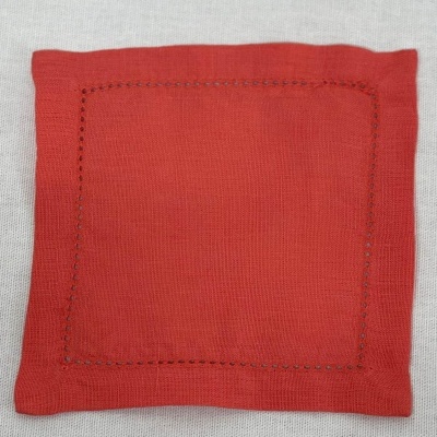 Porta-copos quadrado vermelho com borda decorativa sobre superfície branca.