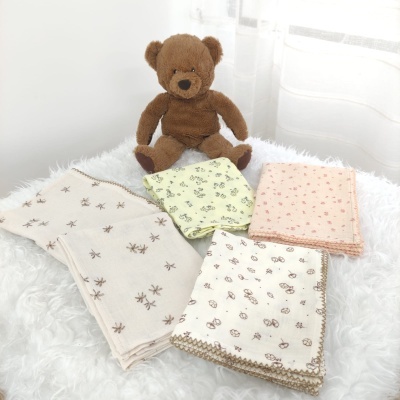 Urso de pelúcia castanho com panos dobrados estampados em superfície branca felpuda