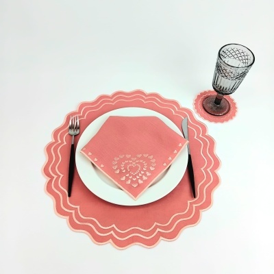 Conjunto de jantar com prato branco, guardanapo rosa recortado, base de prato rosa e copo de vidro transparente