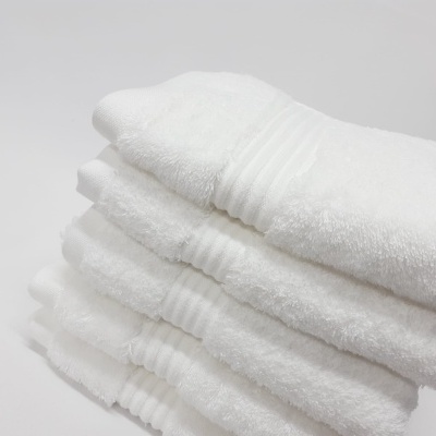 Toalhas brancas de algodão empilhadas com faixa decorativa de linhas em relevo