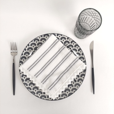 Mesa posta com prato decorado, guardanapo, talheres e copo