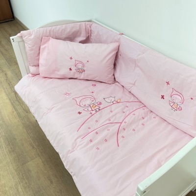 Roupa de cama cor-de-rosa com bordado infantil num berço branco