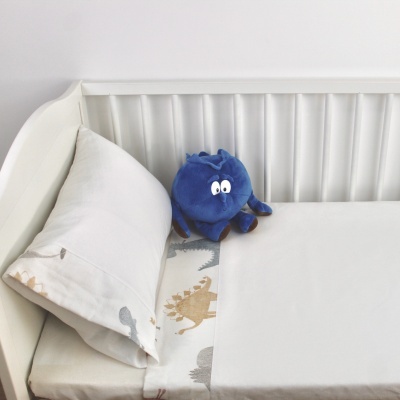 Berço branco com roupa de cama clara e brinquedo de pelúcia azul