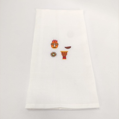 Toalha branca com ícones coloridos costurados no centro.