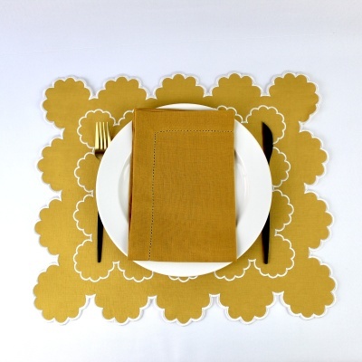 Mesa posta com toalhete e guardanapo dourados, prato branco, garfo e faca pretos