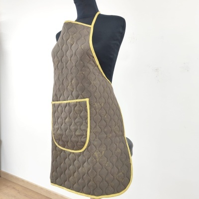 Avental acolchoado castanho com bolso amarelo num manequim preto