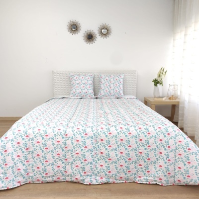 Conjunto de colcha e almofadas com padrão floral rosa e verde em cama com cabeceira branca