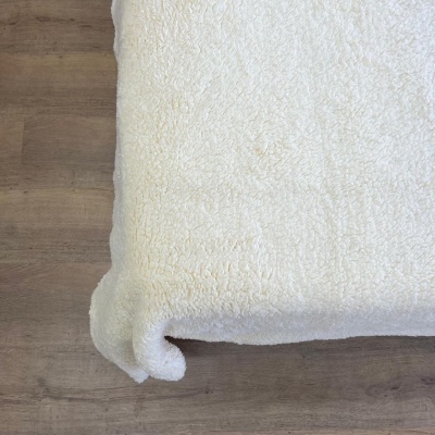 Manta branca felpuda sobre chão de madeira clara