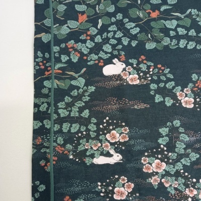 tecido com padrão de coelhos, folhas e flores sobre fundo azul escuro