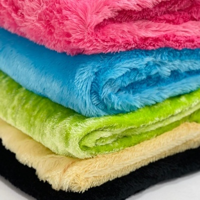 Pilha colorida de mantas felpudas em rosa, azul, verde, amarelo e preto