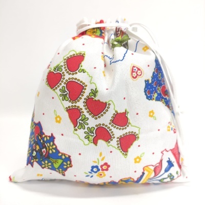Saco de tecido branco com padrão colorido de corações e flores, fecho de cordão branco