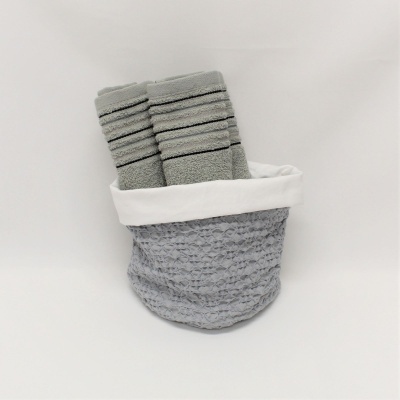 Cesta têxtil cinza com toalhas cinza claro dentro, fundo branco
