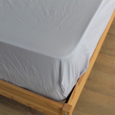 Lençol cinzento claro numa cama de madeira clara com chão de madeira.