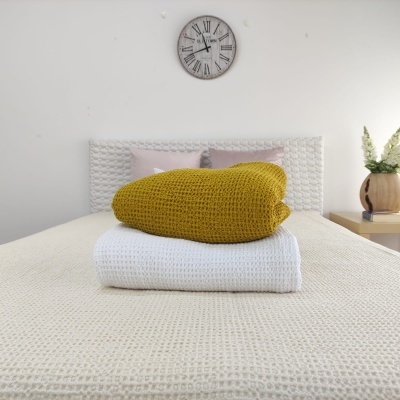 quarto com cama, almofadas, relógio e mantas tricotadas