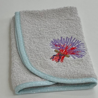 Toalha cinzenta felpuda com bordado colorido e acabamento azul claro dobrada