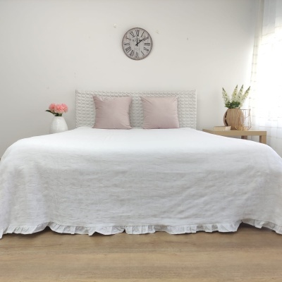 Cama de casal com colcha branca e almofadas rosa em quarto minimalista