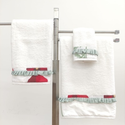 Toalhas brancas com faixa decorativa vermelha e verde em suporte metálico