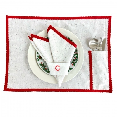Conjunto de mesa com individual e guardanapo branco com bordas vermelhas e letra C bordada, prato decorado e talheres em metal