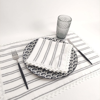 Conjunto de roupa de mesa com guardanapo, passadeira, prato decorativo, talheres pretos e copo translúcido texturizado