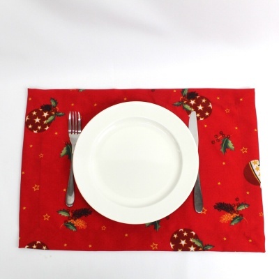 prato branco com talheres sobre individual vermelho com padrão natal