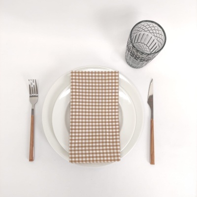 Conjunto de jantar com prato branco, guardanapo xadrez, talheres com cabo de madeira e copo de vidro transparente