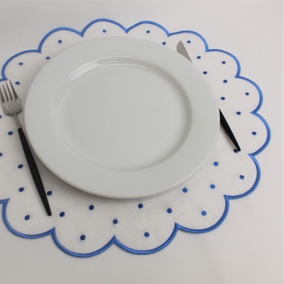 Guardanapo branco com borda azul e pontos azuis, prato branco e talheres com cabos pretos