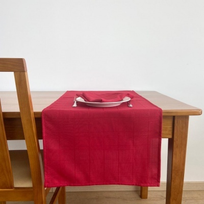 Toalha de mesa vermelha com porta-guardanapos metálico sobre mesa de madeira com cadeira