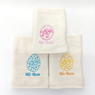 Três toalhas de mão brancas com bordados coloridos de ovo de Páscoa e texto Feliz Páscoa
