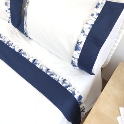Conjunto de roupa de cama branco com detalhes azuis num quarto