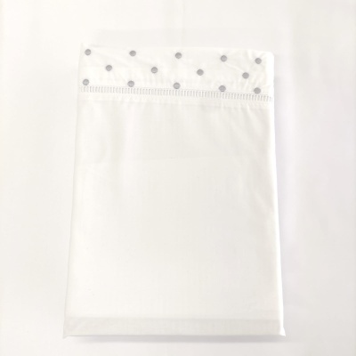 Fronha branca com padrão de círculos cinzentos na faixa superior