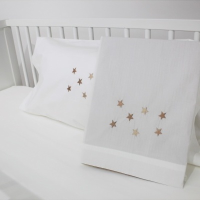 Roupas de cama de berço brancas com estrelas douradas bordadas