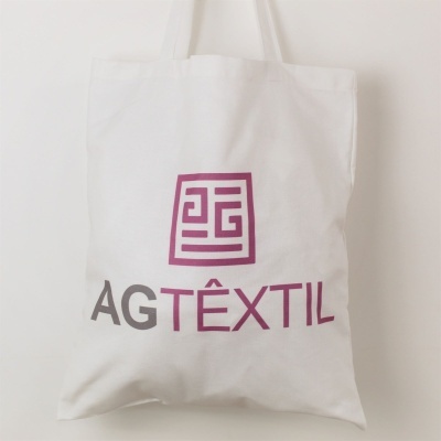 Saco de tecido branco com o texto AGTÊXTIL e um logótipo roxo