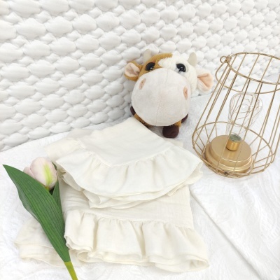 peças de tecido branco creme com babados, brinquedo pelúcia vaca, candeeiro metálico dourado