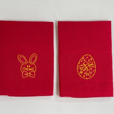 Dois panos de cozinha vermelhos com bordados amarelos de coelho e ovo decorado