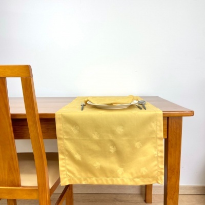 Mesa de madeira clara com toalha amarela e prato com talheres