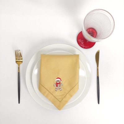 Conjunto de jantar com prato branco, guardanapo decorado, talheres e copo com base vermelha.