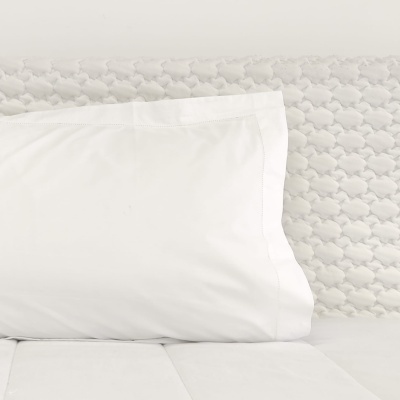 Travesseiro branco sobre cama com colcha texturizada branca