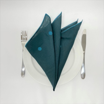 Talheres com prato branco e guardanapo verde escuro com pontos azuis