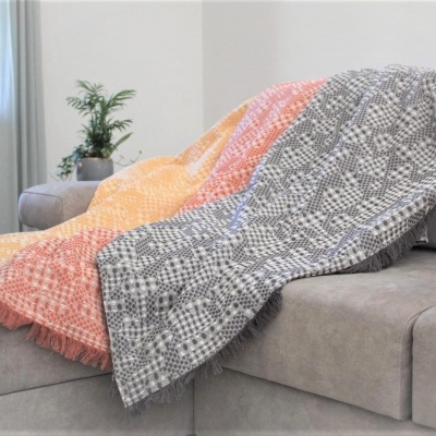 mantas coloridas com padrão geométrico sobre sofá cinza numa sala