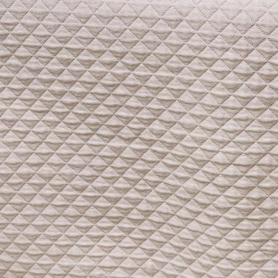Tecido acolchoado bege com padrão de losangos em relevo