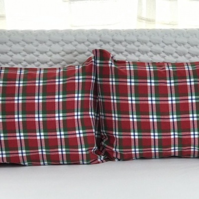 Almofadas retangulares xadrez vermelho em cama com cabeceira branca