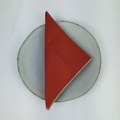 Toalha vermelha dobrada sobre prato cinza redondo