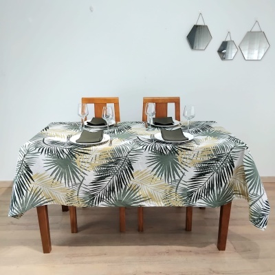 Mesa com toalha estampada de folhas, pratos, copos e guardanapos, em sala com espelhos geométricos na parede