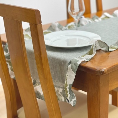 Mesa de madeira com toalha com padrão floral e louça branca