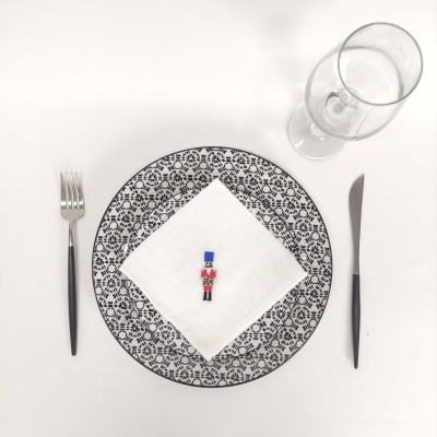 Conjunto de mesa com prato decorativo, guardanapo branco, soldadinho, talheres e copo em fundo branco